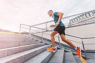 Ein Mann, der ein Sportdress, Sportsocken und Sportschuhe trägt, joggt eine Treppe hinauf.