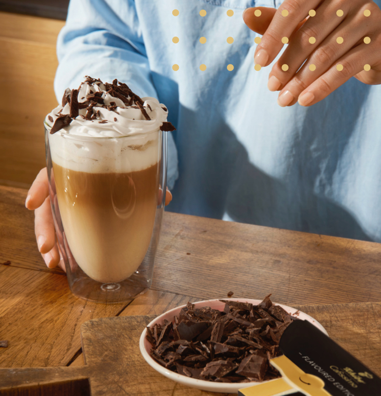 Eine Frau gießet einen Espresso in ein Latte Macchiato Glas, um einen Double Chocochiato zuzubereiten