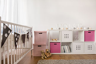 Die richtige Aufbewahrung für mehr Ordnung: Ein Kinderzimmer, an dessen Wand eine weiße Kommode mit verschiedenen würfelförmigen Aufbewahrungsboxen in weiß und rosa steht.