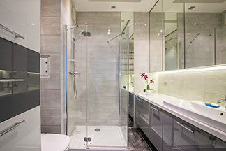 Tipps für kleine Bäder: Ein Badezimmer mit einer großer Spiegelfläche und einer verglasten Dusche.
