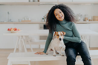 Sitzbank als Mittelpunkt der Küche: Eine junge Frau sitzt mit ihrem Hund auf einer weißen Sitzbank in der Küche.