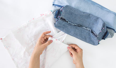 Ein Stoff mit Blumenmuster und blaue Jeansstoff werden abgesteckt