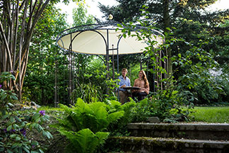 Wohlfühlen im Pavillon: Ein Mann und eine Frau sitzen entspannt unter ihrem Pavillon im Garten.