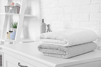 Accessoires für ein gemütliches Bad: Auf einer Kommode im Badezimmer liegen zwei zusammengelegte, weiche Handtücher.