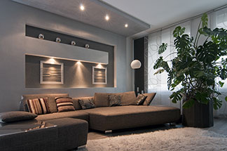 Die richtige Beleuchtung im Wohnzimmer: Verschiedene Lichtquellen sorgen in einem großen Wohnzimmer mit einer braunen Sitzlandschaft für eine stimmungsvolle Atmosphäre.