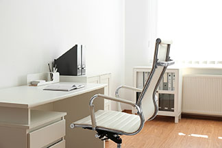 Moderner, ergonomischer Bürostuhl mit weißer Sitzfläche steht an einem weißen Schreibtisch.