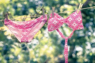 Sport-Bademode richtig pflegen: Ein pink gemusterter Bikini trocknet auf der Wäscheleine.