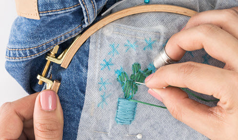 Blütenmotive werden in eine Jeans gestickt