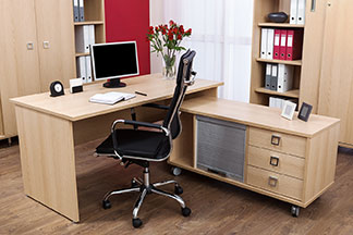 Arbeitsplatz mit hellem Holzschreibtisch und verschiedenen Büroschränken.