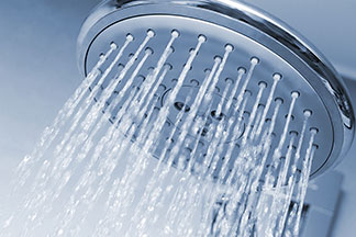 Sanfter Wasserstrahl fürs Wohlbefinden: Ein runder Duschkopf mit heraussprudelndem Wasser.