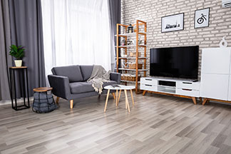 Ein Wohnzimmer mit grauer Couch, weißen Fernsehmöbeln, einem weißen Couchtisch und einem offenen, hohen Holzregal mit weißen Einlegeböden, das an der Wand steht.