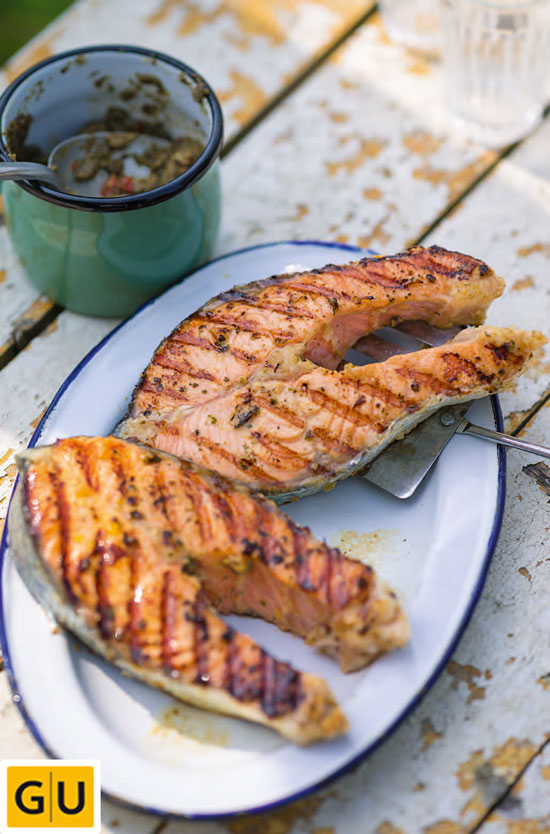 Zwei Lachssteaks in Pastis mit Tapenade auf einem weißen Teller angerichtet.