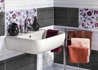 Ein Waschbecken mit geblümten, weißen und grauen Kacheln sorgt für wohnliches Ambiente im Badezimmer.