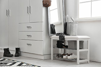 Garderobe mit Stauraum: Ein heller Eineingangsbereich mit einer weißen Kommode mit einer Abdeckplatte aus Holz, die in der Höhe unterschiedlich ist, und somit auch als Garderoben-Bank dient.