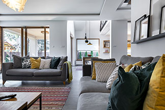 Farbige Deko für das Sofa: Auf zwei grauen Couchen in einem Wohnzimmer liegen viele farbige Kissen.