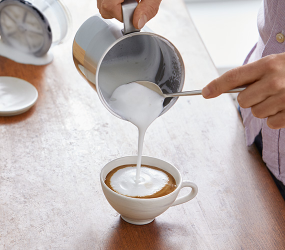 Milchschaum wird auf den Cappuccino gegeben