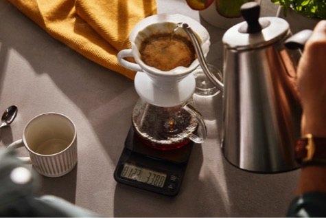 Kaffee wird durch einen Handfilter geschüttet.
