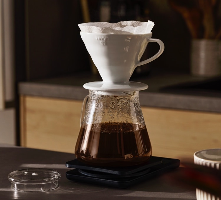Kaffee läuft durch einen Keramikhandfilter in eine Glaskanne. Dieser Abschnitt befasst sich mit der klassischen Filterzubereitung.