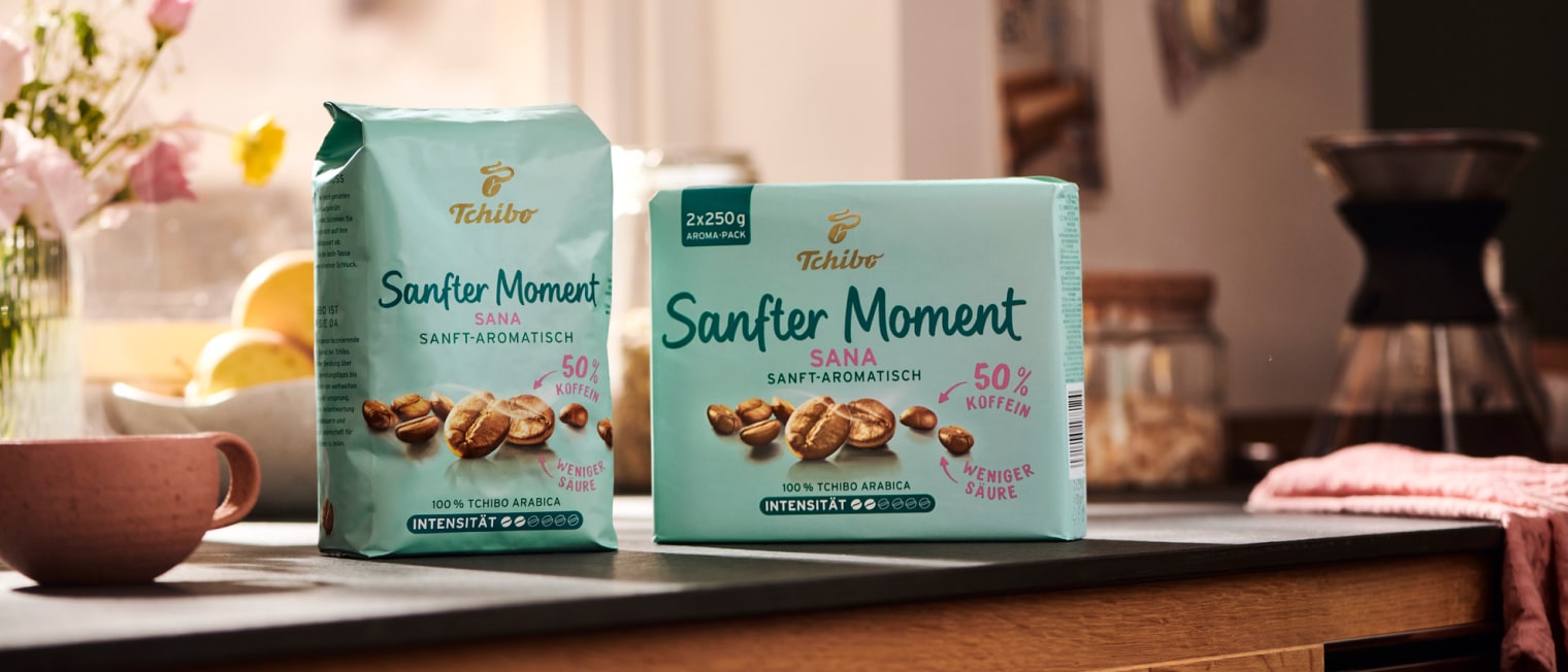 eine Packung 'Sanfter Moment - gemahlen' und eine Packung 'Sanfter Moment - ganze Bohnen' stehen einem Küchentisch','Enter picture alt'}