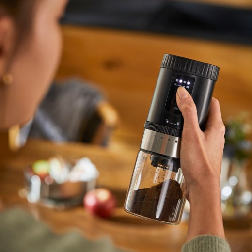Frau hält Akku-Kaffeemühle in der Hand