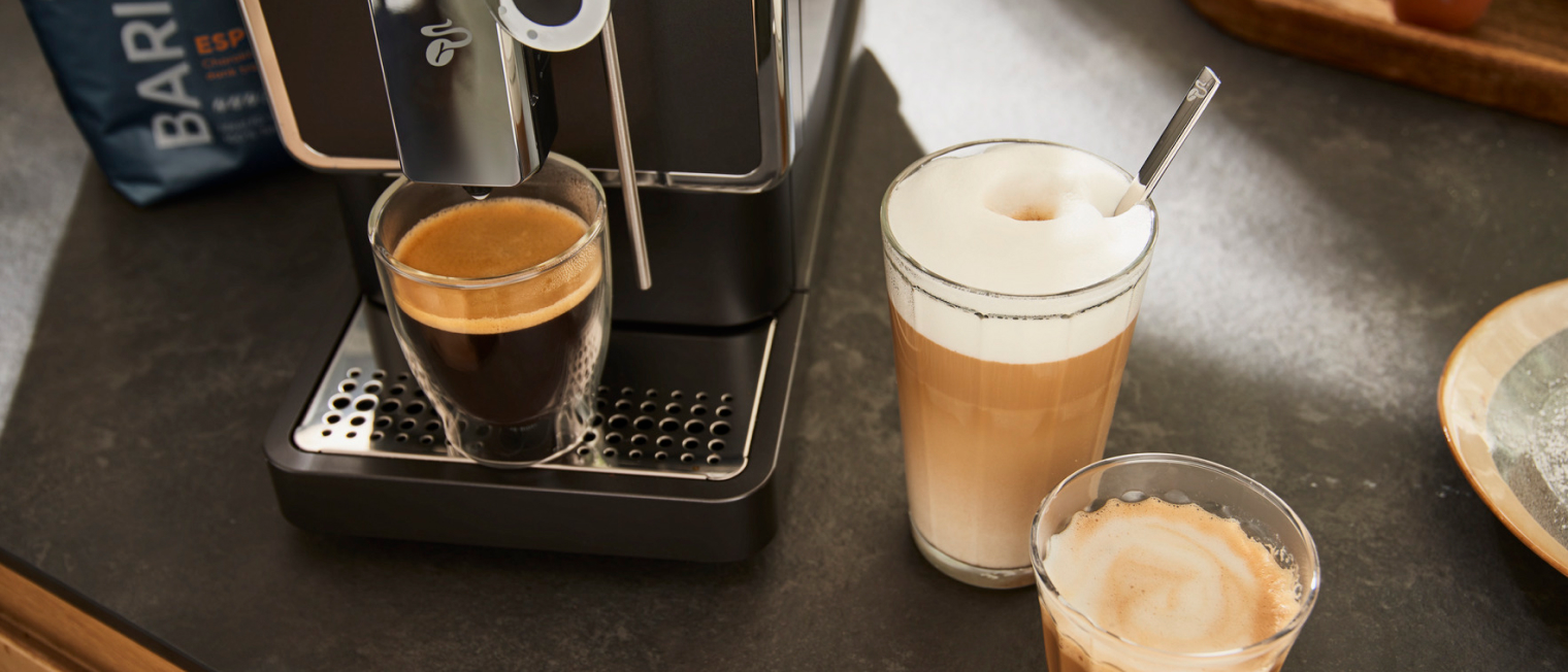 Drei Getränke ein Latte Macchiato, ein Espresso und ein Kaffee stehen auf einer Küchenzeile, zubereitet von einem Vollautomaten.