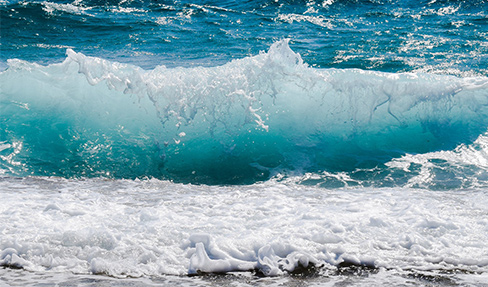 Eine Welle im Meer bricht am Strand um