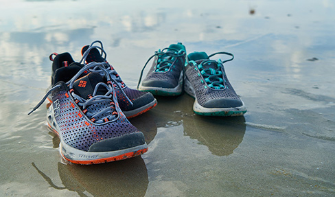Zwei Paar Sportschuhe am Strand
