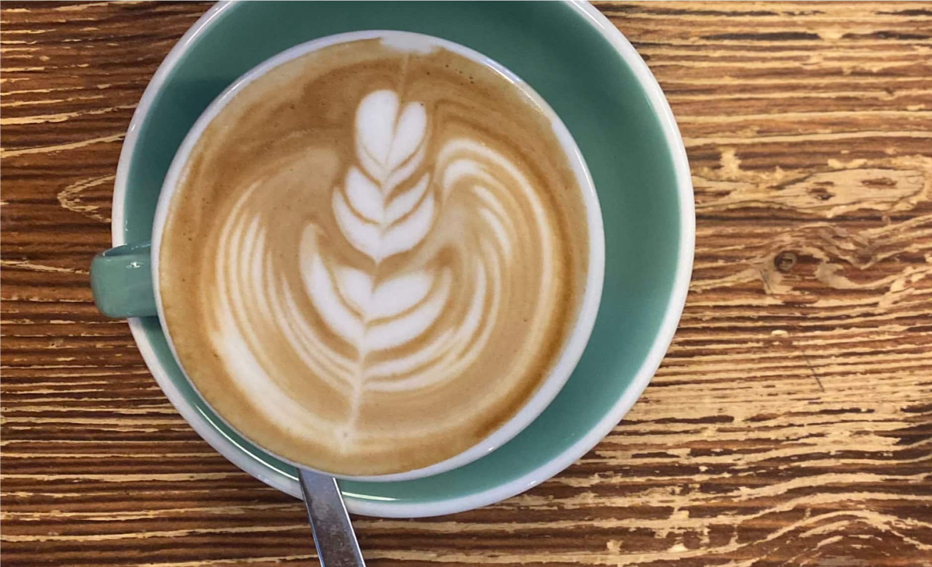 Eine Tasse Kaffee mit Latte Art steht auf einem Holztisch