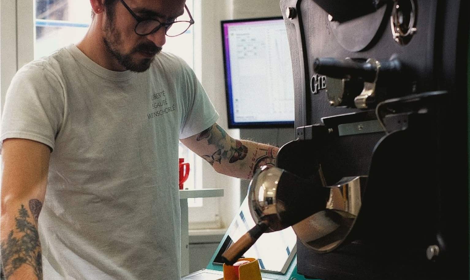 Ein Mitarbeiter der Rösterei Buena Vida Coffee Club steht vor einer Röstertrommel