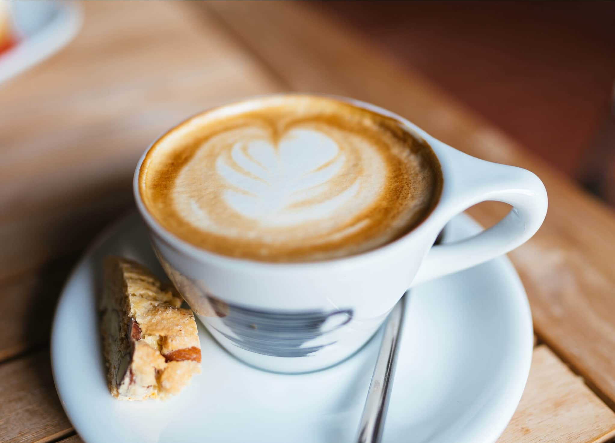 Nahaufnahme von Capuccino Tasse mit Latte Art auf Holztisch