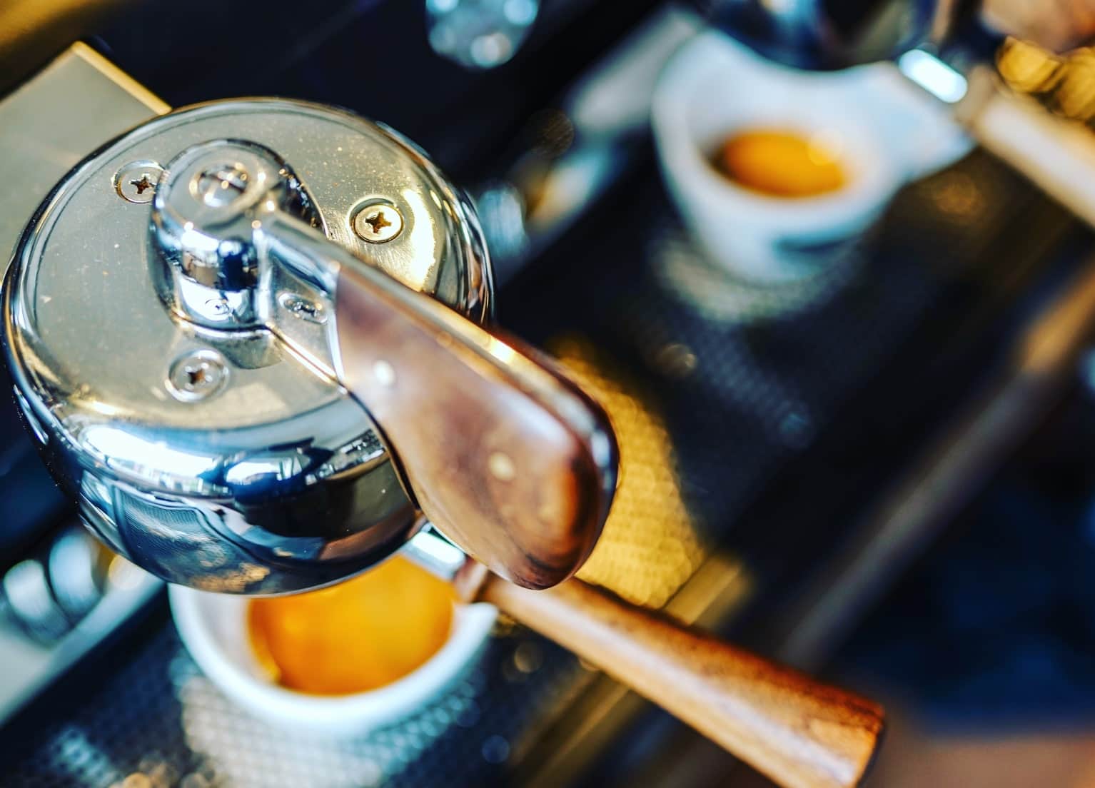 Nahaufnahme von Brühgruppe einer Siebträgermaschine unter der ein Espresso steht