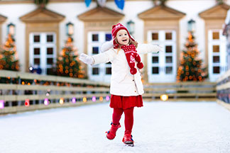 Ein kleines Mädchen trägt weiße Handschuhe umgeben von einer Winterlandschaft.