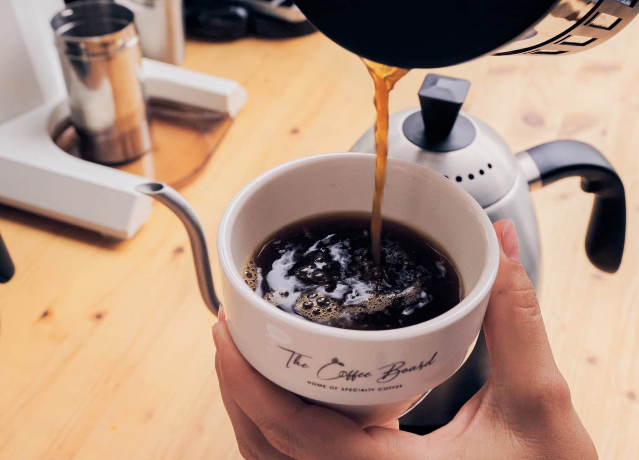 Kaffee läuft in eine Tasse mit dem Logo von The Coffee Board