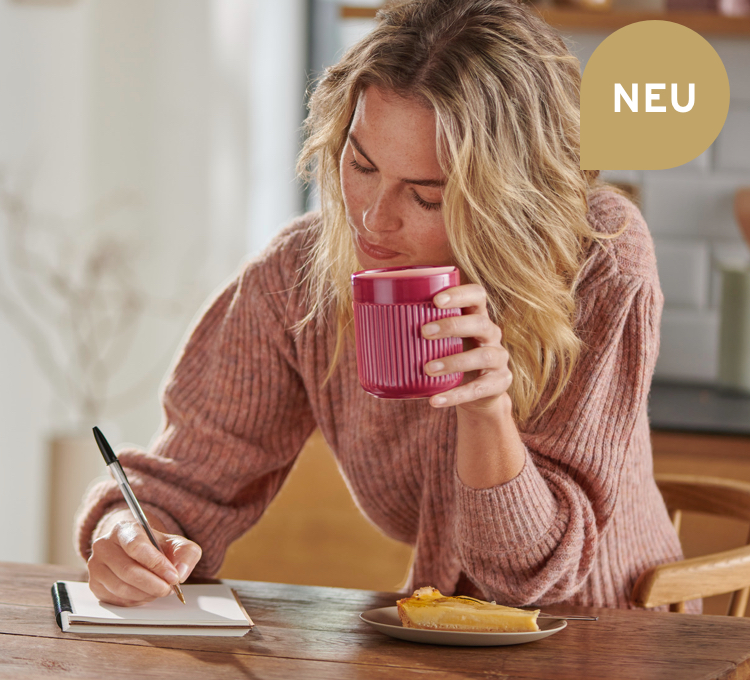 Eine Frau trinkt ihren Kaffee aus einem rosa Kaffeebecher der Porzellanserie.