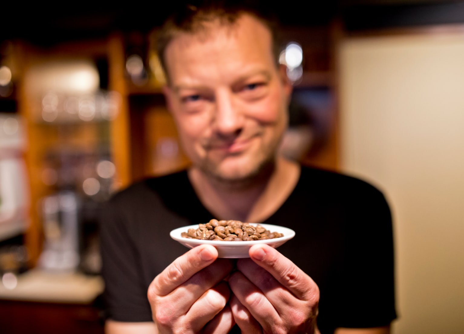 Inhaber Oliver hält Kaffeebohnen in die Linse