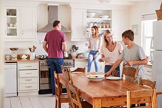 Eine Familie bereitet den Esstisch in Ihrer gut sortierten Küche vor.